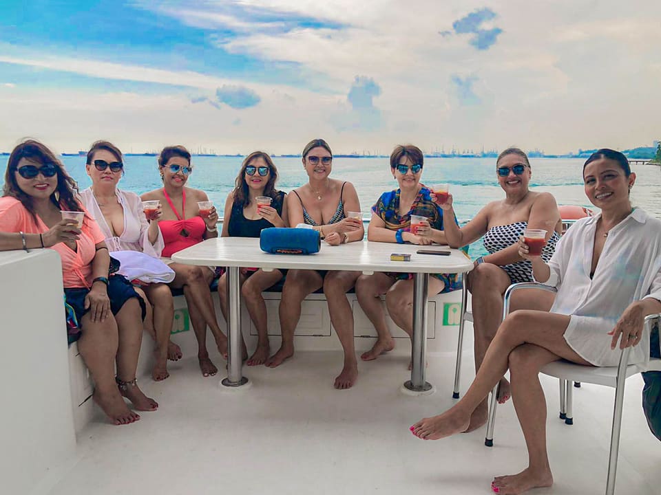 Nine guests sitting around the flybridge table with drinks in hand, the shipping lanes on the horizon behind them
