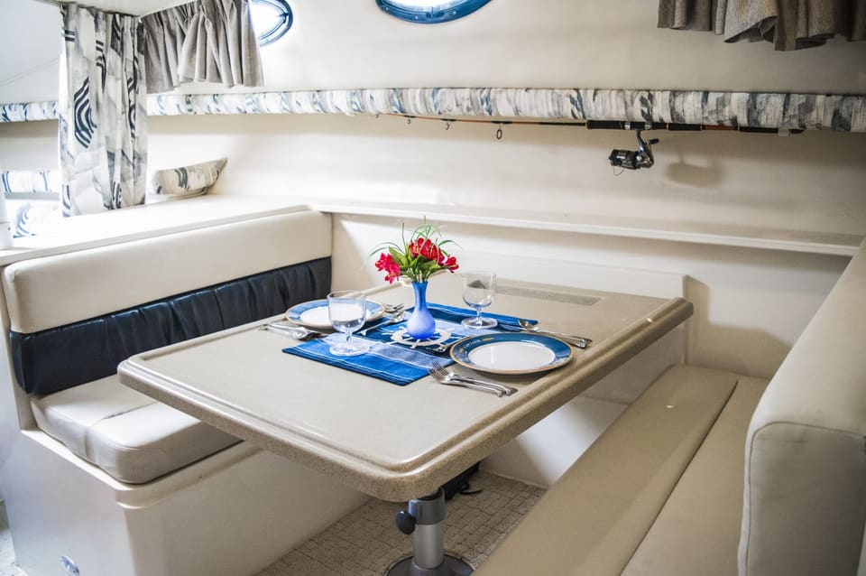 Dinette below set for four, with fishing rods stowed in the rack overhead