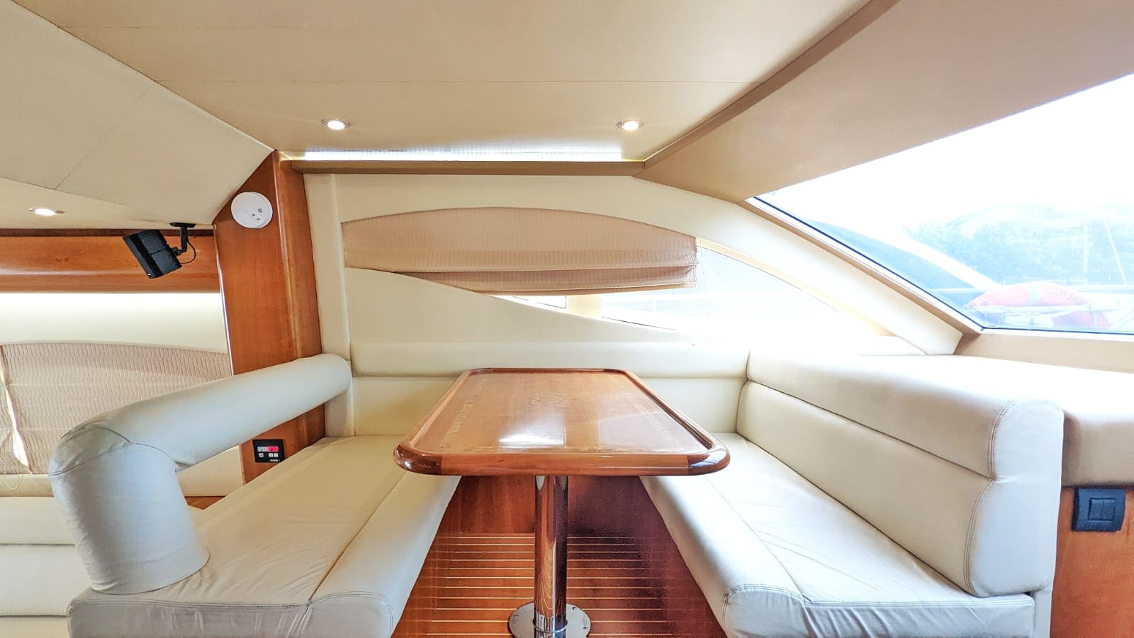 Air-conditioned saloon below, with a polished table between cream leather banquettes and a window over the marina