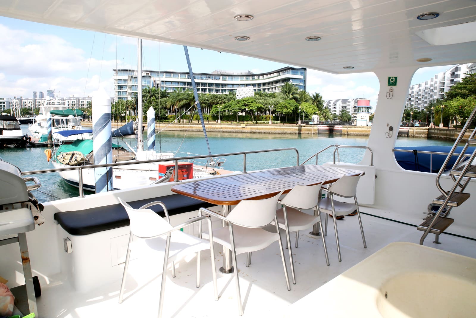 Covered aft deck with a teak dining table and six chairs, looking out over ONE°15 Marina