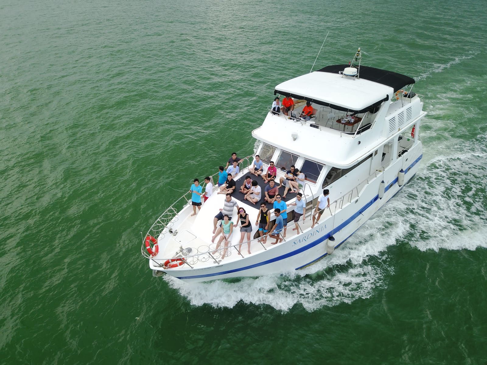 Overhead view of guests spread across Sardinia's bow sun pad while underway