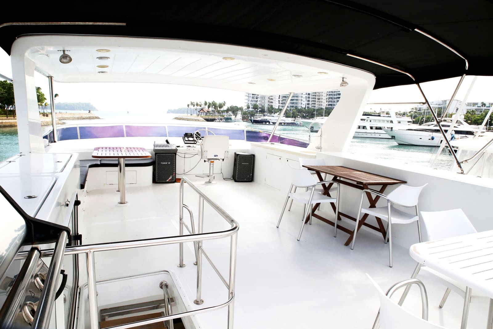 Wide view of the bimini-shaded top deck with the sound system set up beside the upper helm