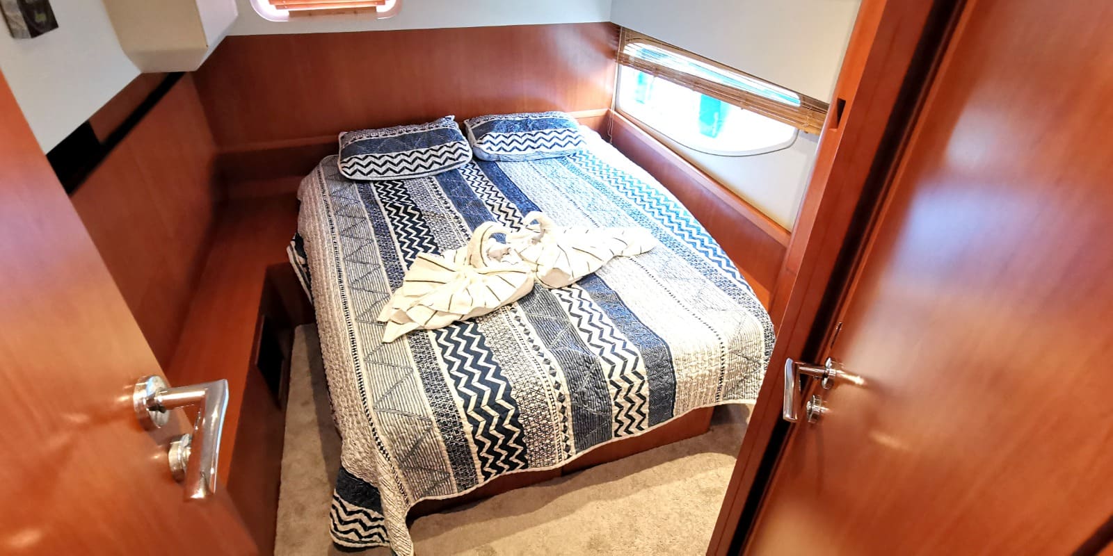 One of the two cabins, with a made-up double berth and a hull window