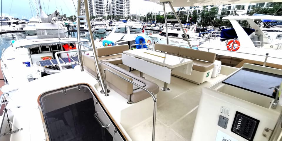Flybridge alongside at ONE°15 Marina, with bench seating around a table and the Sentosa Cove apartments behind