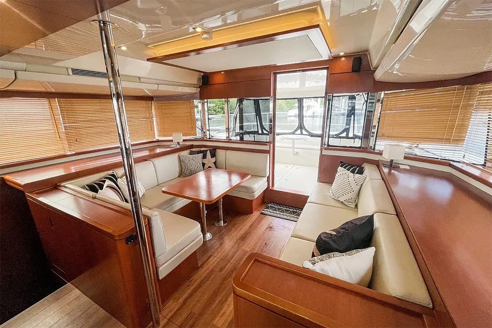 Wraparound saloon seating around a dining table, with the aft doors open to the cockpit